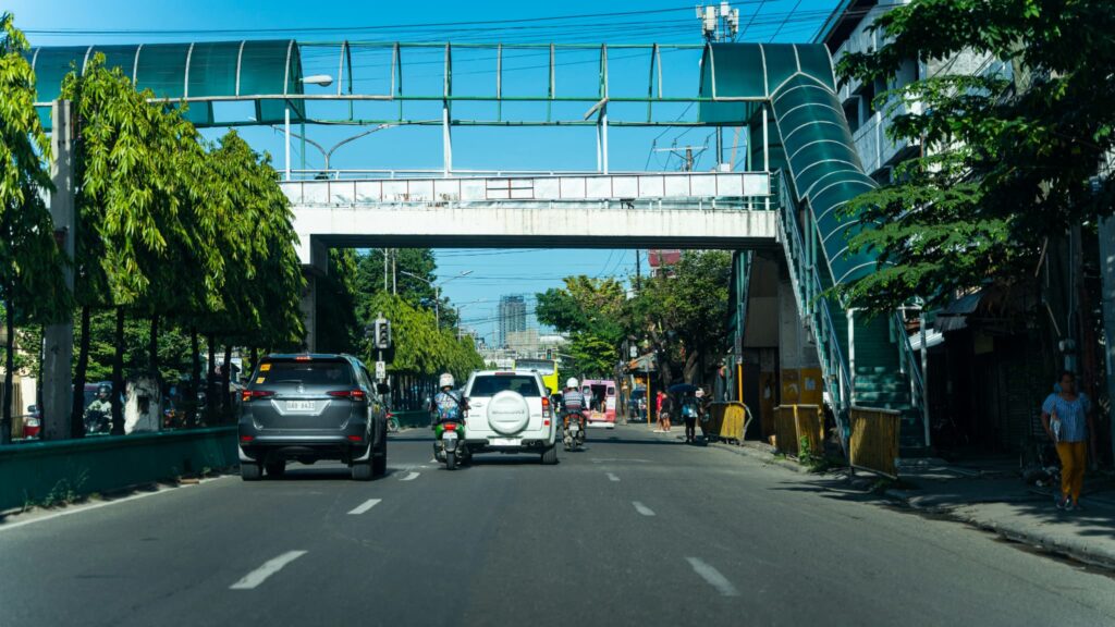 緑色の屋根が付いた歩道橋が架かる、セブ島の交通量の多い幹線道路。