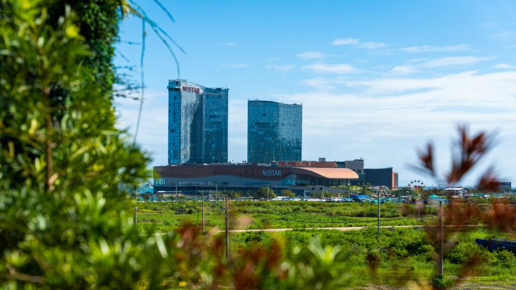 青空の下、緑地の向こう側に見えるセブ島の複合リゾート施設「NUSTAR」のビル群。