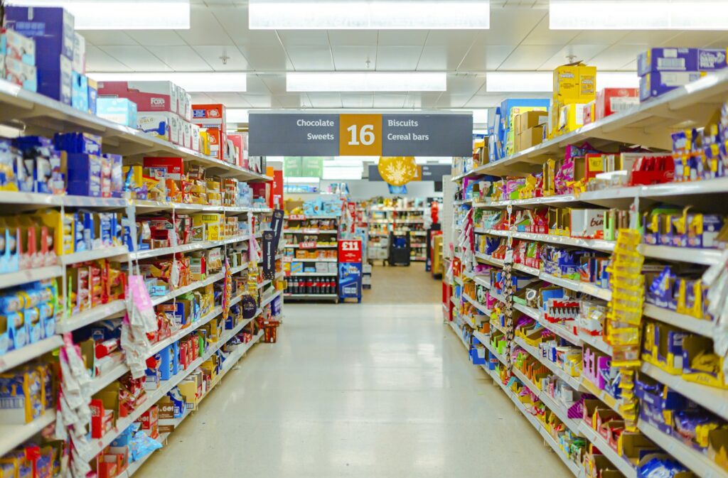 お菓子や食品がぎっしり並ぶ、明るいスーパーの通路